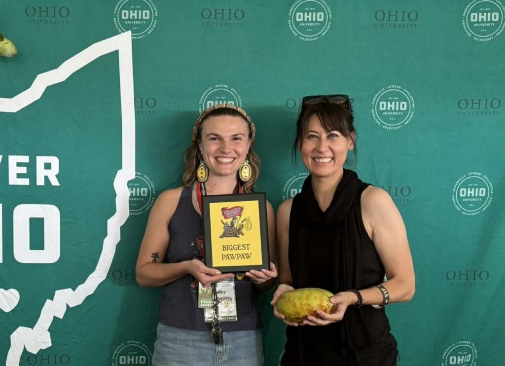Valerie Libbey holding the 965-gram Susquehanna pawpaw that won Biggest Pawpaw at the 2026 Ohio Pawpaw Festival