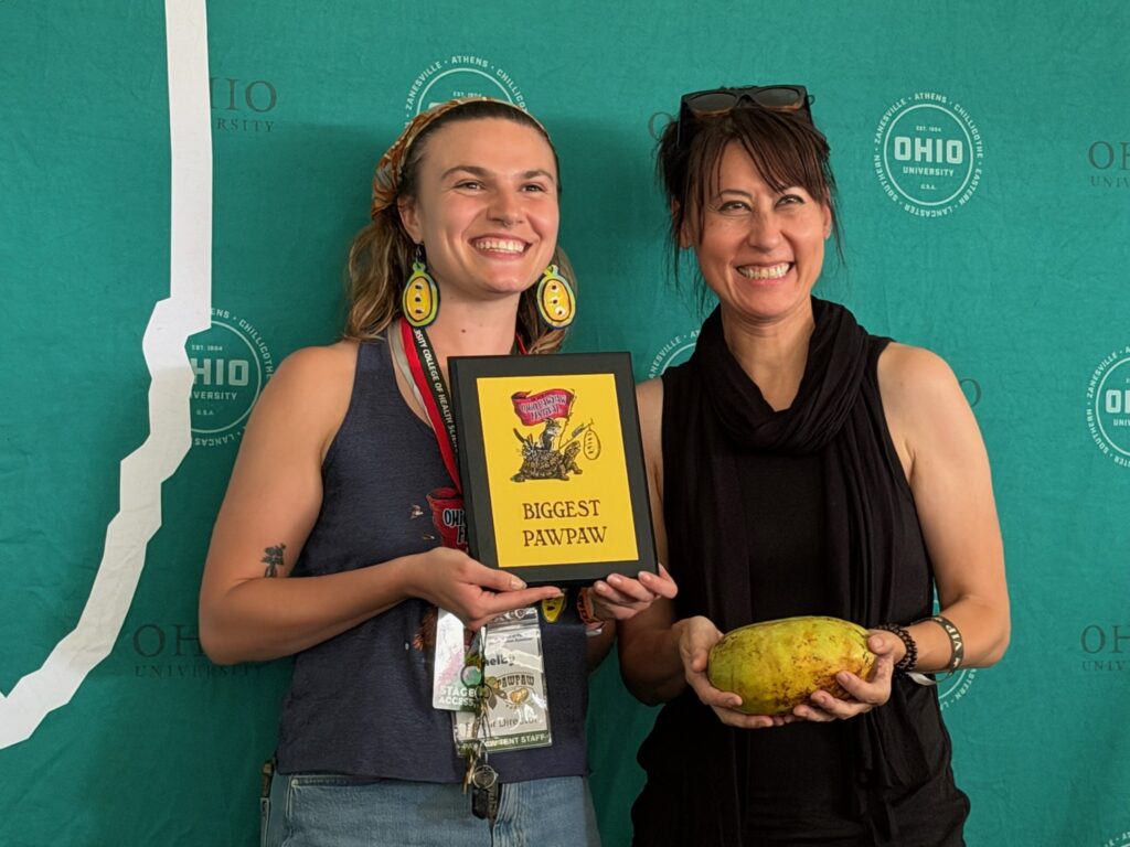 Valerie Libbey holding her first-place 965-gram Susquehanna pawpaw at the 2026 Ohio Pawpaw Festival Biggest Pawpaw competition.